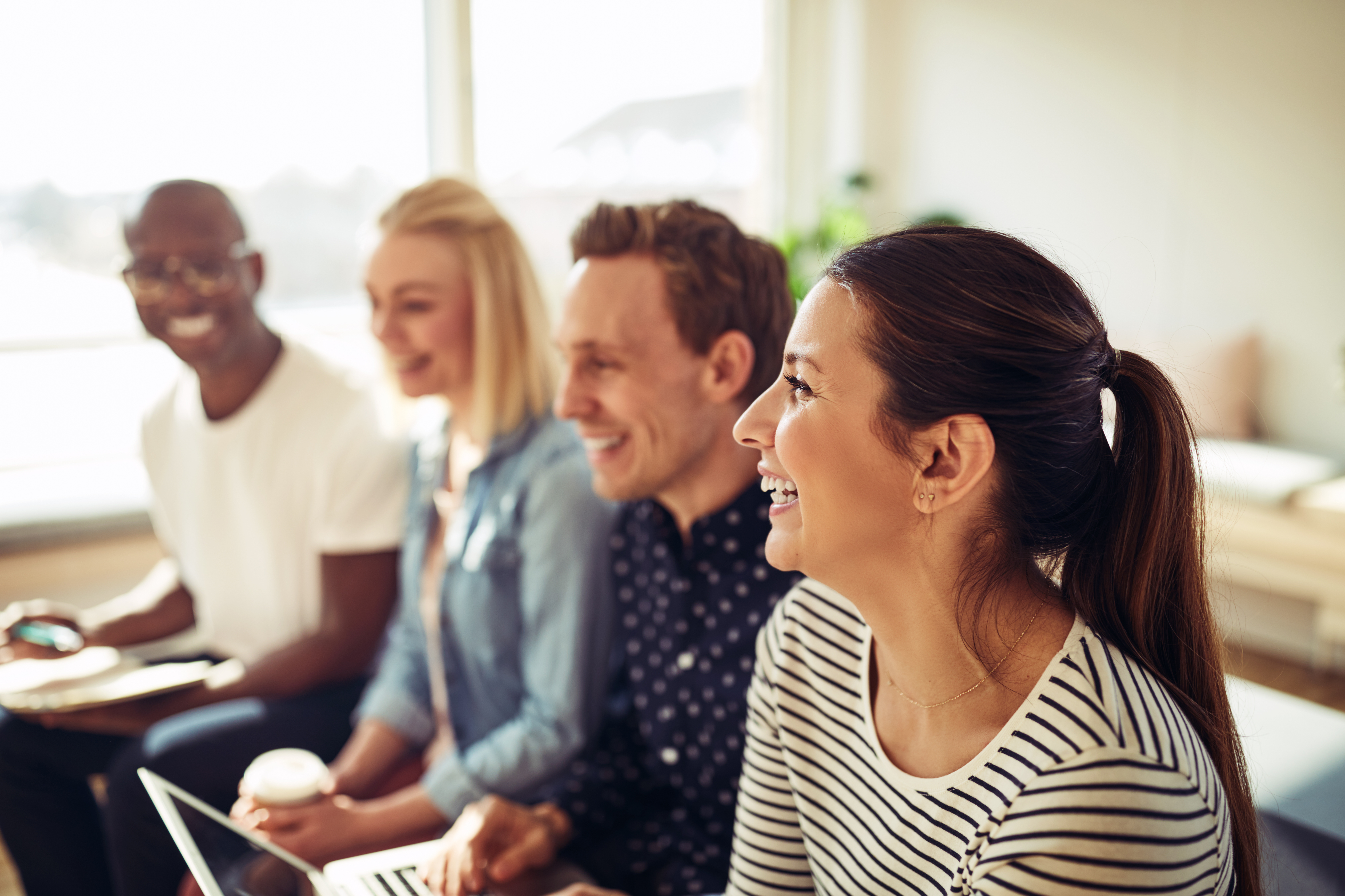 Four employees sitting next to each other smiling