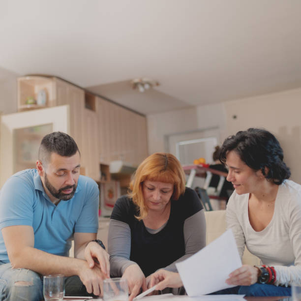 A woman talking to a couple with paper in front of them